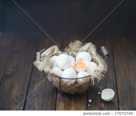 Eggs in wire basket on dark wooden table 27073740