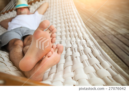 Man in hat in a hammock on a summer day Man in hat in a hammock on a summer day 27076042