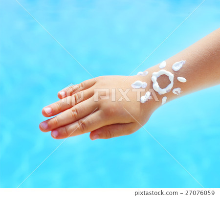 Hand of the baby with suntan lotion near the pool 27076059