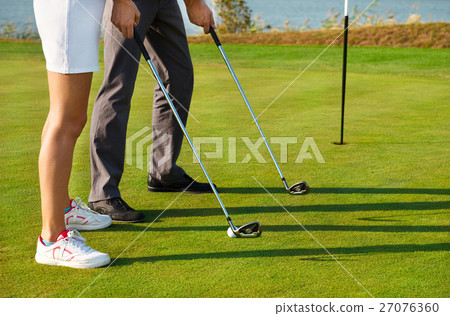 Young sportive couple playing golf on golf course Young sportive couple playing golf on golf course 27076360