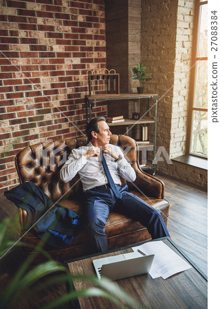 Thoughtful tired man taking off tie Thoughtful tired man taking off tie 27088384