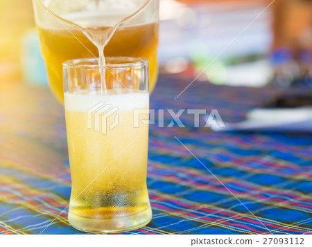 Pour beer into a glass, on Dining table . Pour beer into a glass, on Dining table . 27093112