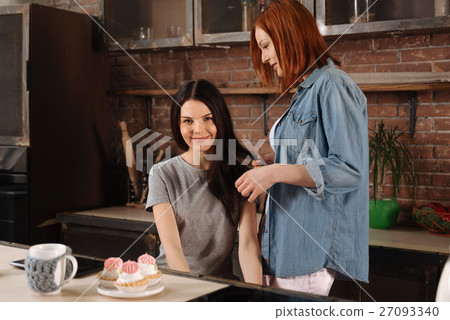 Red haired female doing hair of her friend 27093340