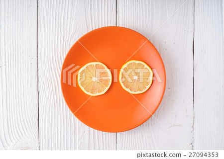 Round slices of lemon on orange plate Round slices of lemon on orange plate 27094353