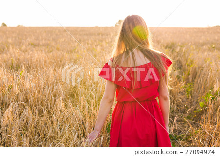 Girl in red dress on the field. Rear view Girl in red dress on the field. Rear view 27094974