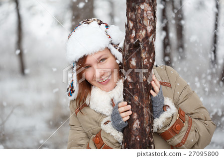 Happy smiling woman in coat with white fur, hat with ear flaps a 27095800