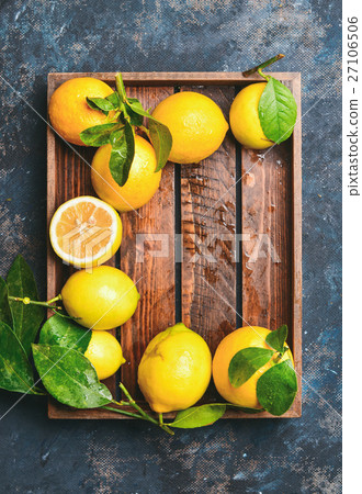 Freshly picked lemons with leaves in wooden tray 27106506