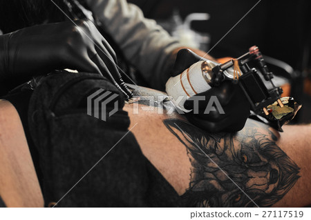 Tattoo master is tattooing in the tattoosalon Tattoo master is tattooing in the tattoosalon 27117519