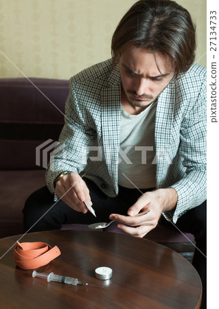 Narcotic dependence man preparing a dose of heroin Narcotic dependence man preparing a dose of heroin 27134733