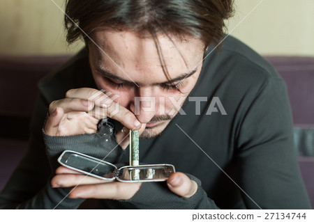 Addict man smells cocaine from a mirror. 27134744