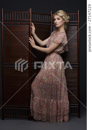 Beautiful girl standing near folding screen  27147229
