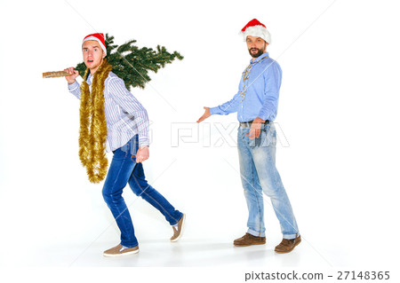 The young man in Santa cap carrying Christmas tree 27148365