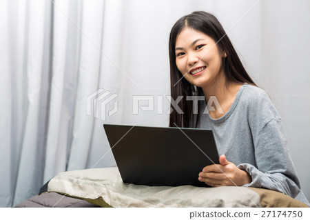 Asian young lady sitting on bed uing lapt Asian young lady sitting on bed uing lapt 27174750