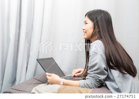 Portrait of women sitting on bed use laptop Portrait of women sitting on bed use laptop 27174751