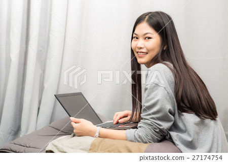 Happy girl using modern laptop smiling on bed Happy girl using modern laptop smiling on bed 27174754