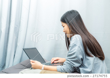 Asian young lady sitting on bed uing lapt Asian young lady sitting on bed uing lapt 27174755
