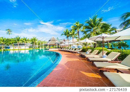 Umbrella and chair around swimming pool 27176439