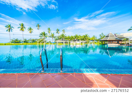 Umbrella and chair around swimming pool 27176552