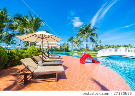 Umbrella and chair around swimming pool 27180656