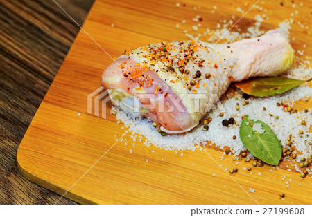 Raw chicken drumsticks on cutting board.  27199608