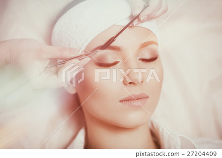 Beautiful young woman gets eyebrow correction Beautiful young woman gets eyebrow correction 27204409