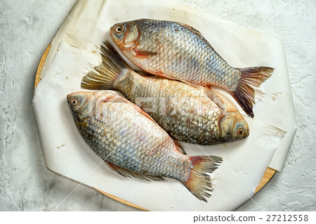 Three fresh carp on a cutting board with paper 27212558