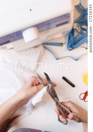 Woman cuts thread in fabric 27216343