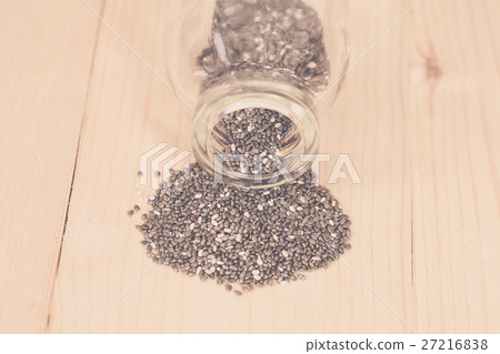 chia seeds spilling out of glass bottle on wood 27216838