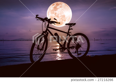 Silhouette of bicycle on beach against full moon. 27218266
