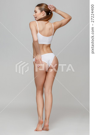 Slim tanned woman's body over gray background 27224400