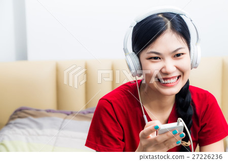 attractive asian woman listening music on bed attractive asian woman listening music on bed 27226236