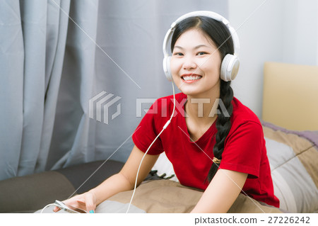 attractive asian woman listening music on bed attractive asian woman listening music on bed 27226242