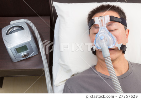 Asian man with sleep apnea using CPAP machine Asian man with sleep apnea using CPAP machine 27257629