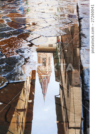 tower reflected in puddle on street 27260041