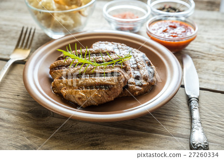 Beef steaks on the wooden background 27260334