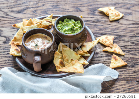 Bowls of guacamole and queso with tortilla chips 27260581