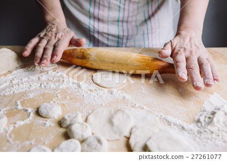 Making meat dumpling with wooden rolling pin. 27261077