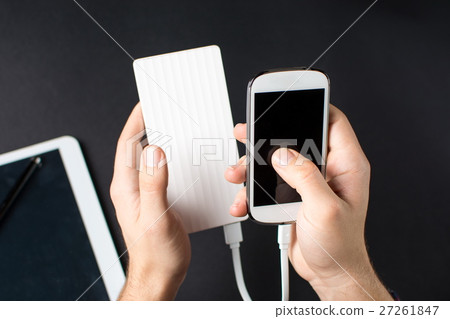 holding white cellphone connected to a power bank 27261847