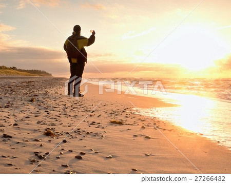Man takes photo of evening sea.Hiker with backpack 27266482