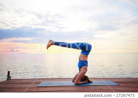 Young woman practicing yoga on the sunset beach 27267473