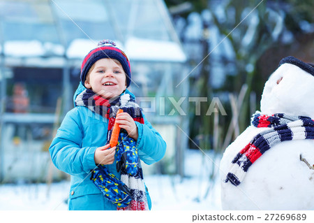 Funny kid boy making a snowman in winter outdoors Funny kid boy making a snowman in winter outdoors 27269689