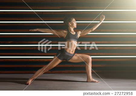 Young woman doing yoga exercises in dark studio Young woman doing yoga exercises in dark studio 27272958