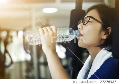 Asian woman drinking water after her workout. Asian woman drinking water after her workout. 27276387