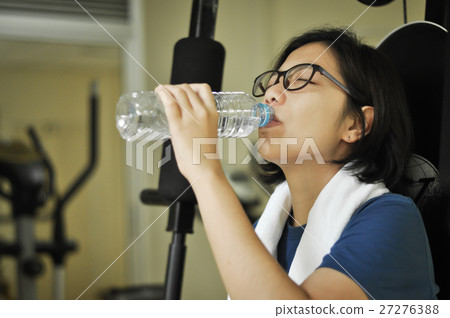 Asian woman drinking water after her workout. Asian woman drinking water after her workout. 27276388