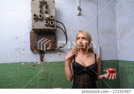 Woman left in a corridor with candle 27282997