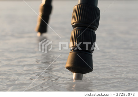 Tripod legs with ice spikes standing on clear ice 27283078