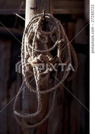 Twisted rope hanging on a wooden pole in the barn Twisted rope hanging on a wooden pole in the barn 27288722