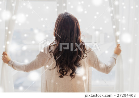 close up of woman opening window curtains 27294408