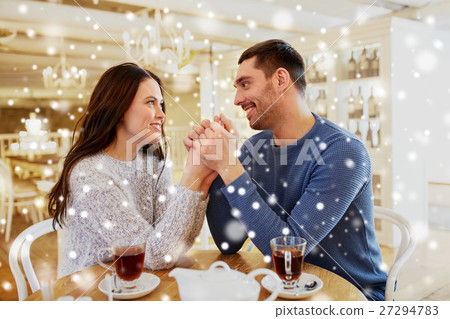 happy couple with tea holding hands at restaurant 27294783