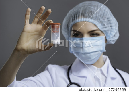 Concentrated female doctor holding a pill box Concentrated female doctor holding a pill box 27296269